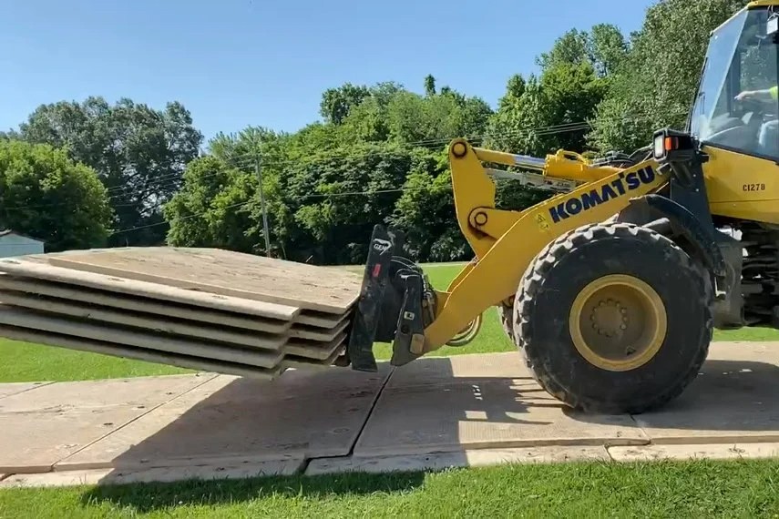 Forklift bringing MegaDeck HD mats over a field